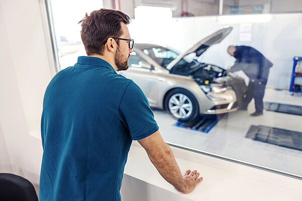 Mann im blauen Shirt überwacht Produktionsprosess im Automobilbau
