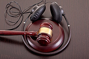 Konzeptbild über Musikpiraterie und Urheberrechtsschutzgesetz mit Hammer und Kopfhörern auf Tischplatte