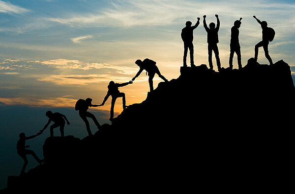 Mitarbeiter erklimmen einen Berg und helfen sich