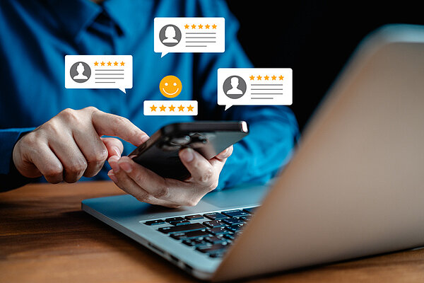 Bewertungsplattformen im Griff: So steuern Unternehmen ihre Online-Reputation professionell ezensionen, Bewertung, Diskussion. Telefon mit Fünf-Sterne-Bewertung. Hände mit Daumen hoch und Daumen runter.