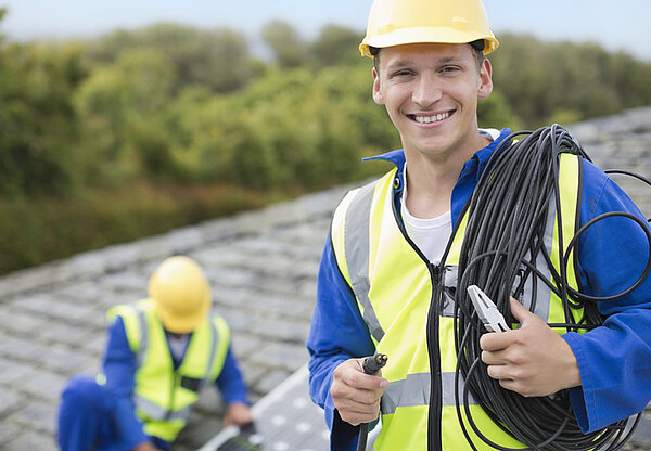Lächelnde Handwerker auf Dach bei PV Anlage