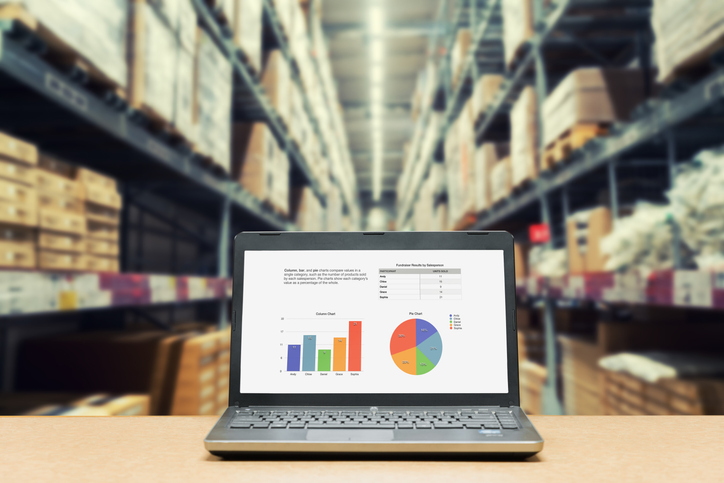 Laptop mit Verkauf Auswertungsbildschirm auf Tisch mit blur Lager Fracht im Werk. Konzept der smart Factory.